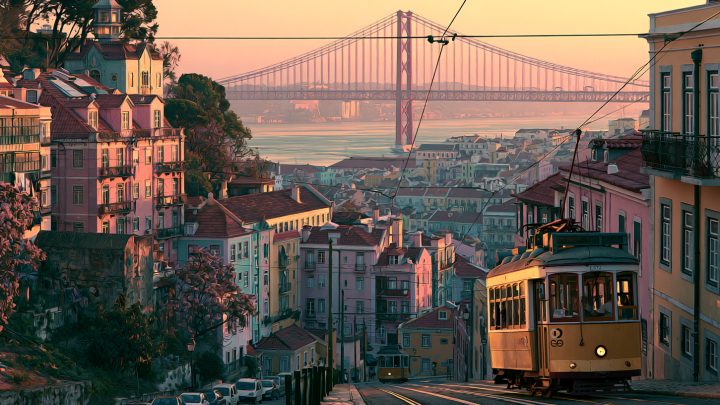 Lissabon mit gelber Straßenbahn und der Ponte 25 de Abril im Abendlicht